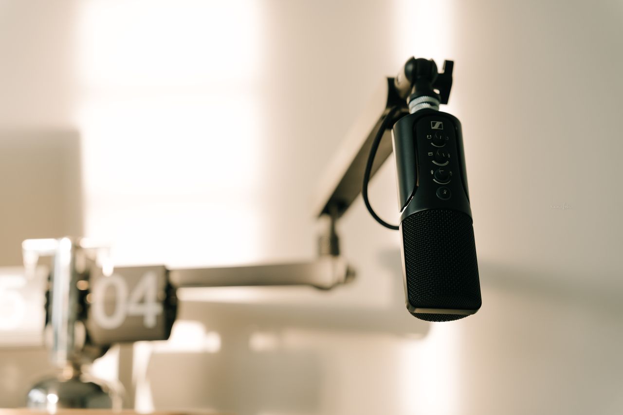 services-01 A sleek professional microphone on a boom arm in a minimalist studio.